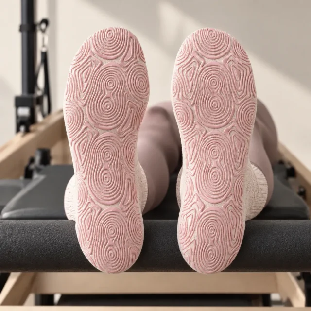 Heels in grip socks against a reformer footbar